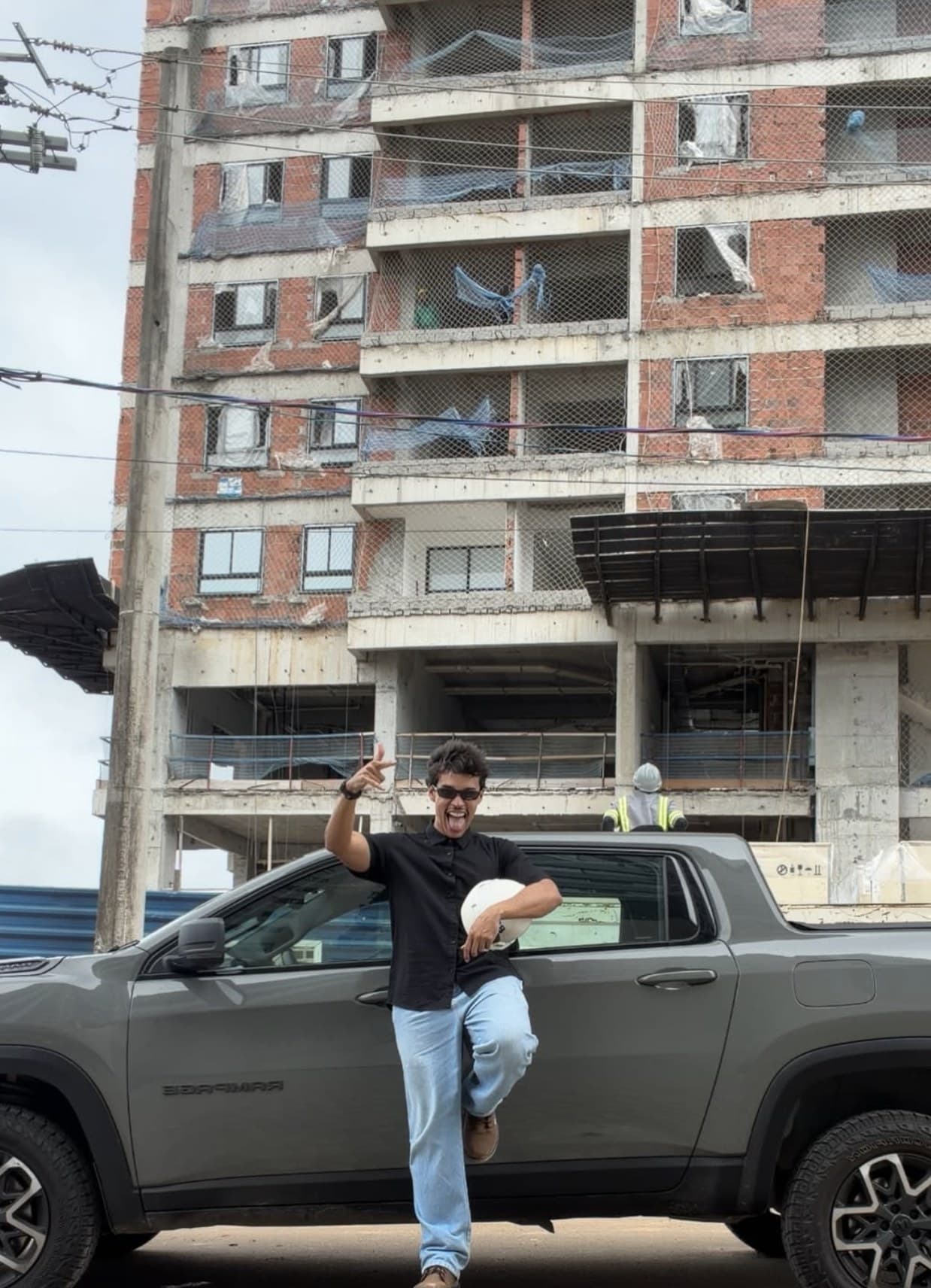 Lipe na frente da pickup, com prédio em obra atrás